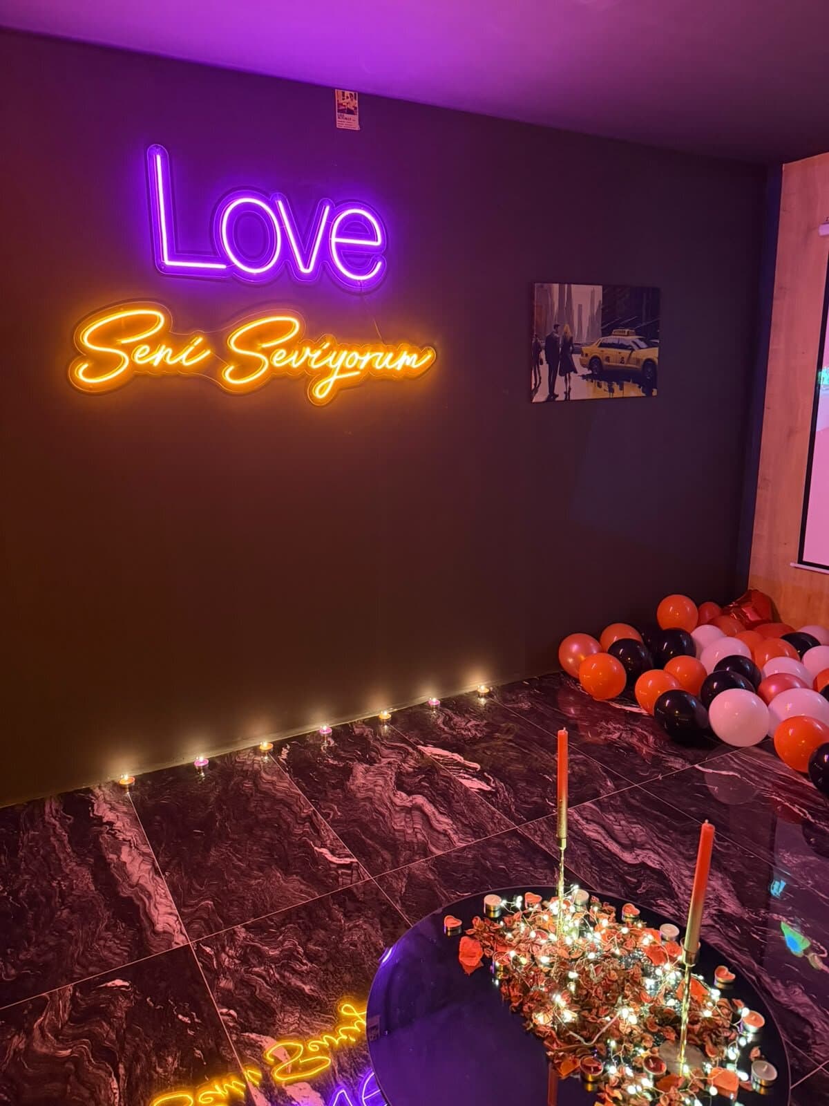 Odada Love ve Seni Seviyorum neonları, zemin boyunca mum sırası ve balonlar