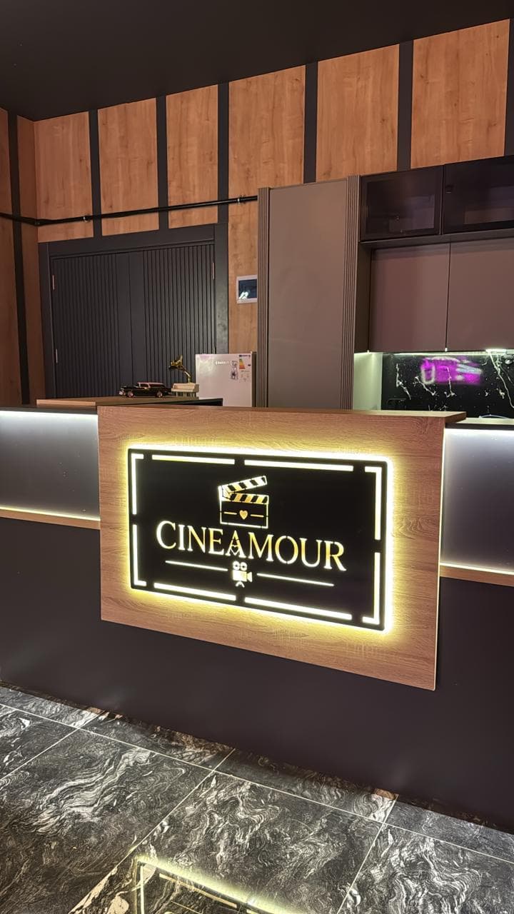 Cineamour resepsiyonu: ahşap bankonun üzerinde ışıklı altın logo